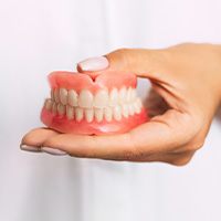 dentist holding dentures in hand