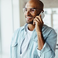 Man with glasses smiling while talking on phone