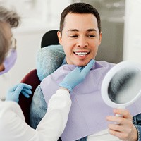 Man smiling at reflection in mirror with dentist