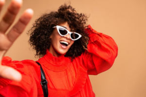 Woman smiling and posing on a tan background